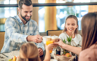 Family enjoying breakfast at Brasserie Rosalie, toasting with coffee and juice.