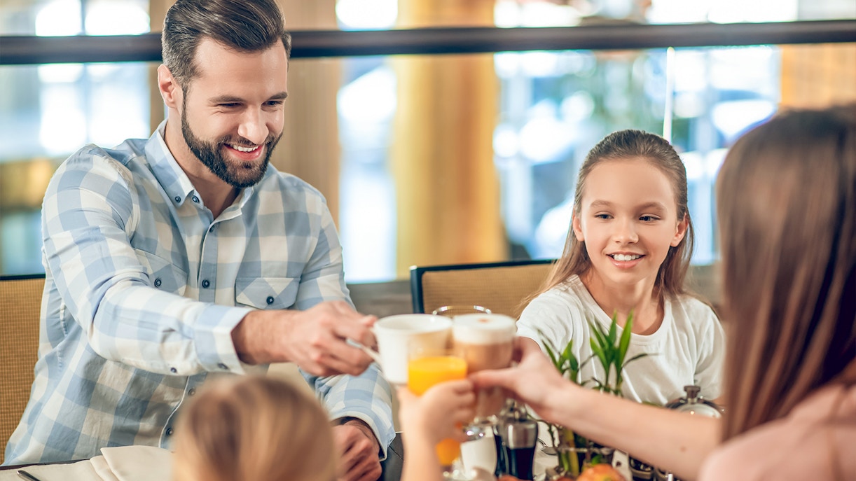 Family enjoying breakfast at Brasserie Rosalie, toasting with coffee and juice.