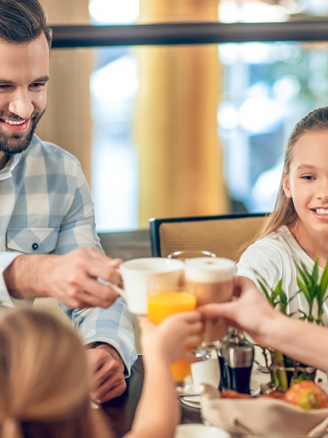 Family enjoying breakfast at Brasserie Rosalie, toasting with coffee and juice.