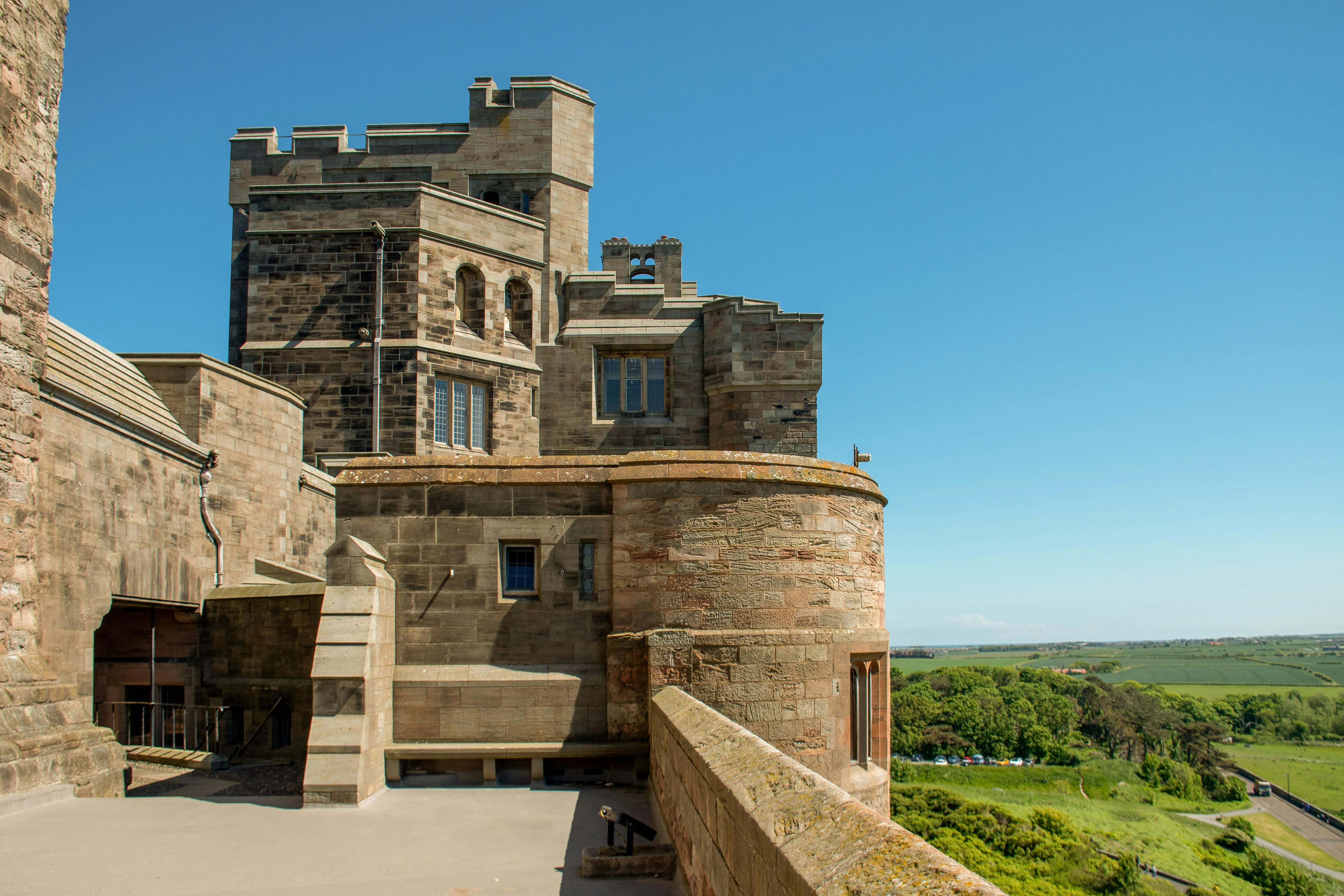 Bamburgh Castle interior view with stone walls and countryside landscape.