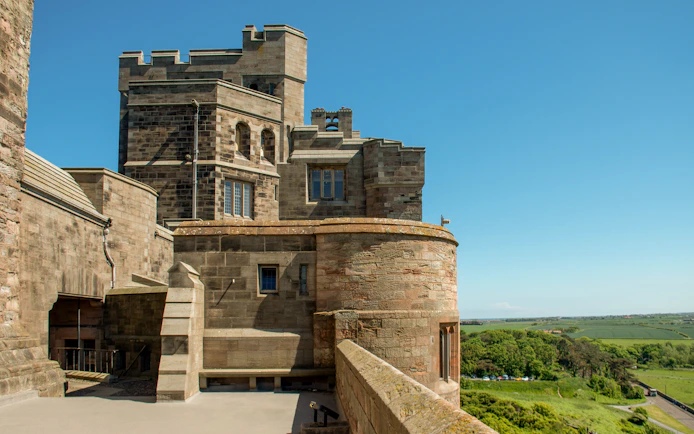 Bamburgh Castle interior view with stone walls and countryside landscape.