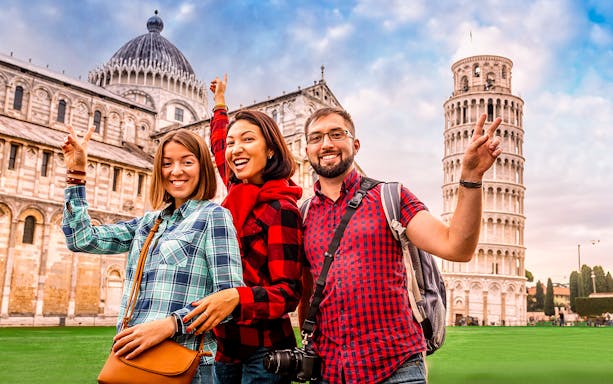 Tourists posing in front of Pisa Cathedral and Leaning Tower during guided tour.
