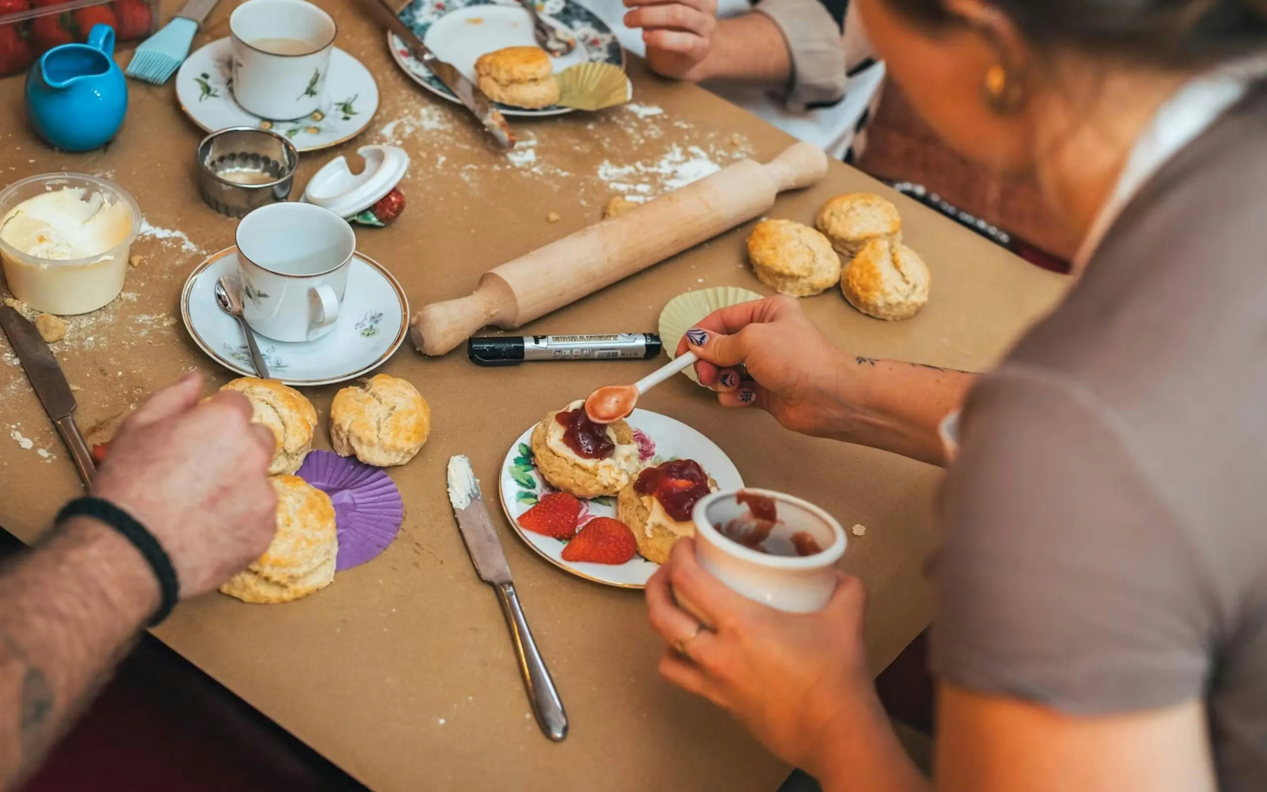Scone-making workshop in London with participants adding jam and cream to freshly baked scones.