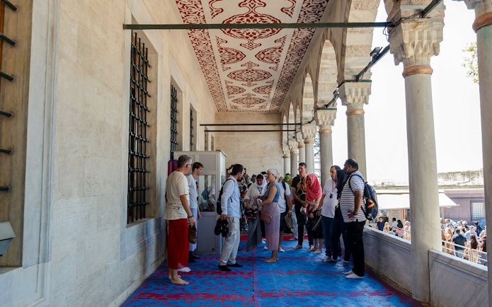 Visitors on a guided tour at Hagia Sophia, Istanbul, standing on a decorated balcony.