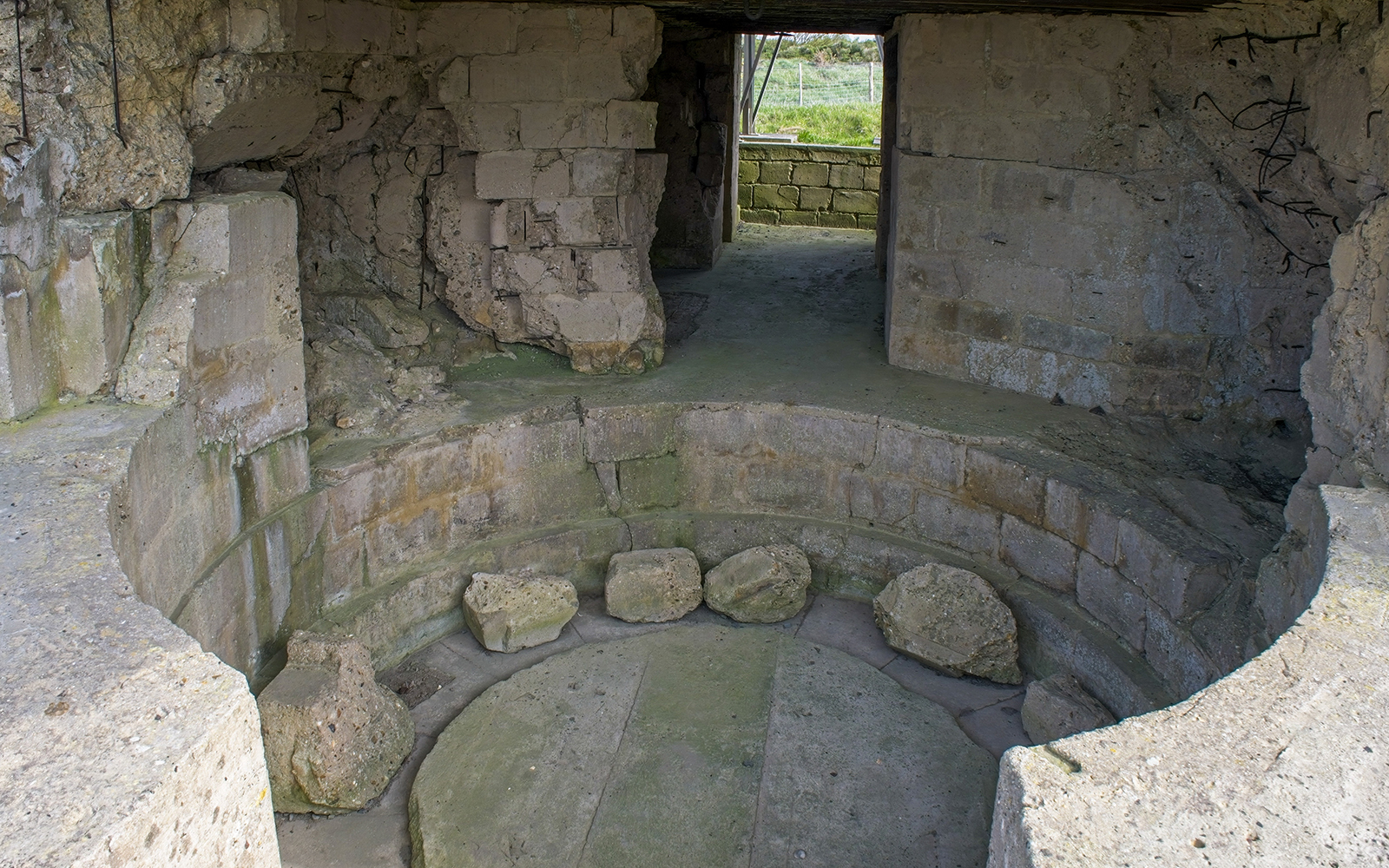 Normandy D-Day bunker interior with stone walls and circular structure.