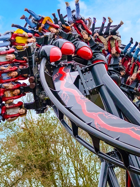 Riders upside down on Nemesis Reborn roller coaster at Alton Towers.