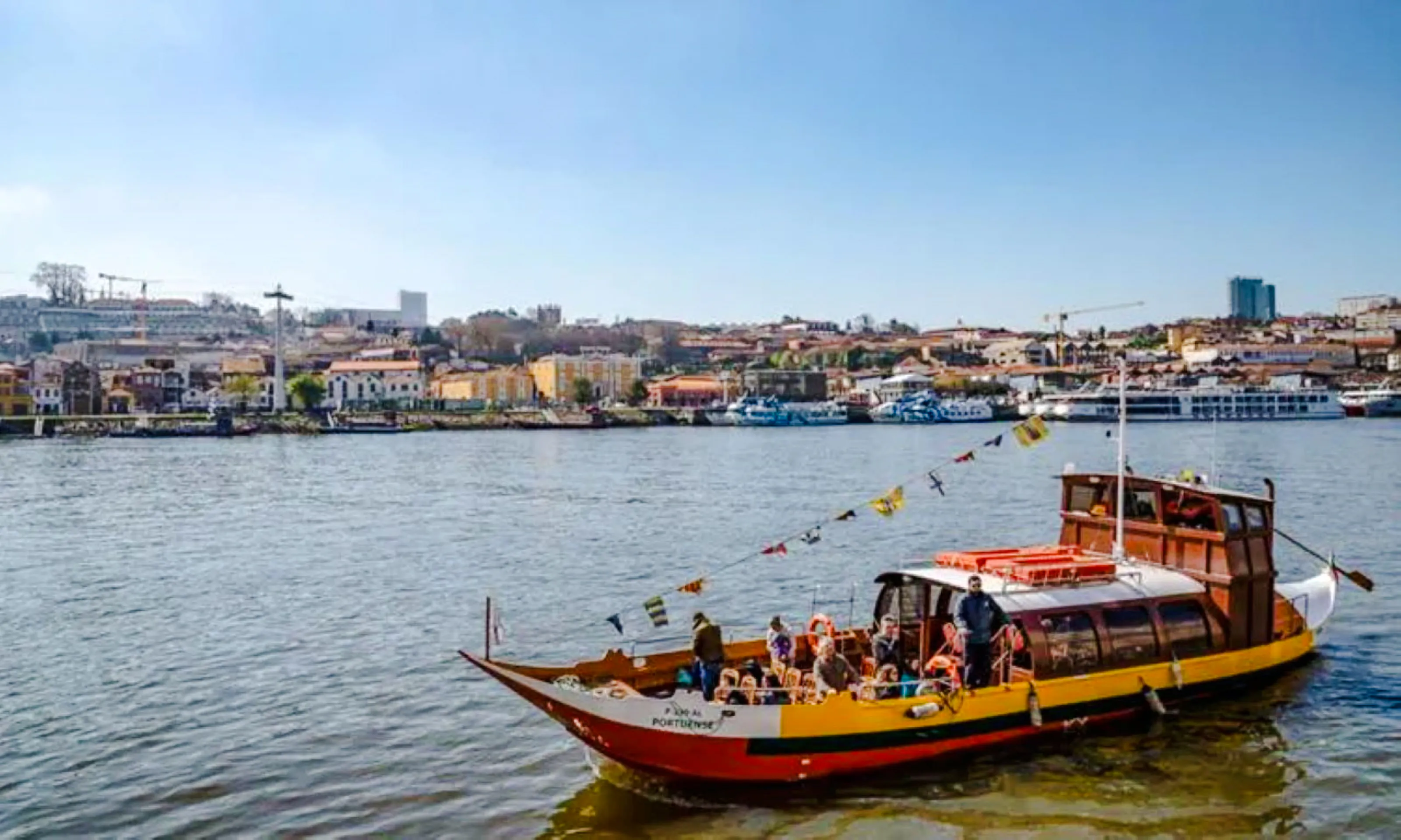 Traditional boat on Douro River with Porto cityscape in background.