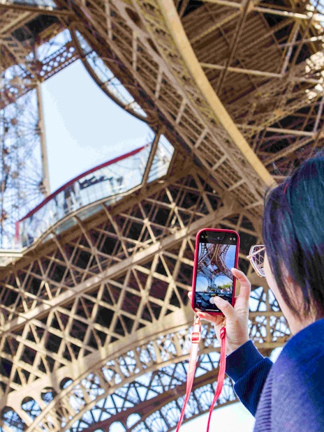 Person photographing Eiffel Tower structure during Paris Illumination Tour.