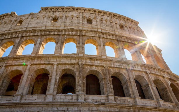 Colosseum in Rome with sunlight streaming through arches.