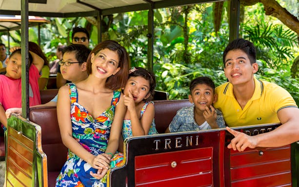 Family enjoying a tram ride through lush greenery at Sunway Lost World of Tambun.
