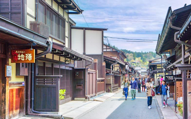 Street view of traditional wooden buildings in Takayama, Japan, with tourists exploring.