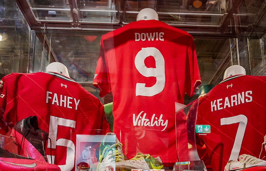 Liverpool FC jerseys displayed in museum exhibit.