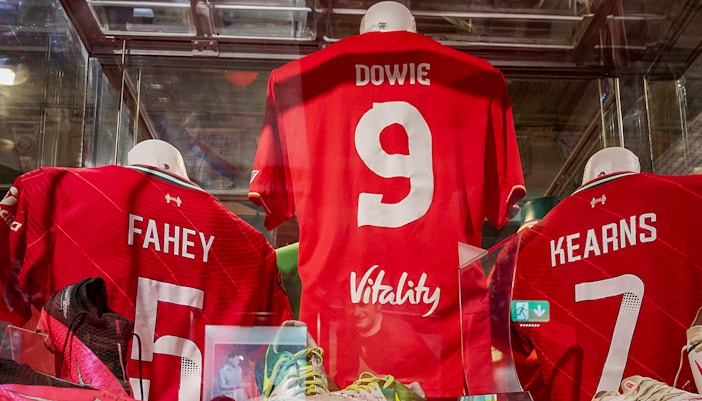 Liverpool FC jerseys displayed in museum exhibit.