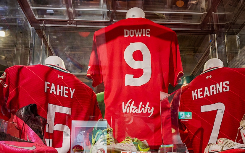Liverpool FC jerseys displayed in museum exhibit.