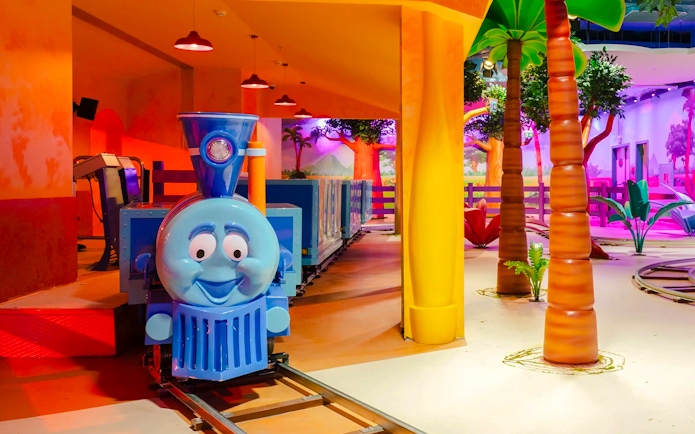 Train ride inside Nickelodeon Play City, Istanbul with colorful decor and palm trees.
