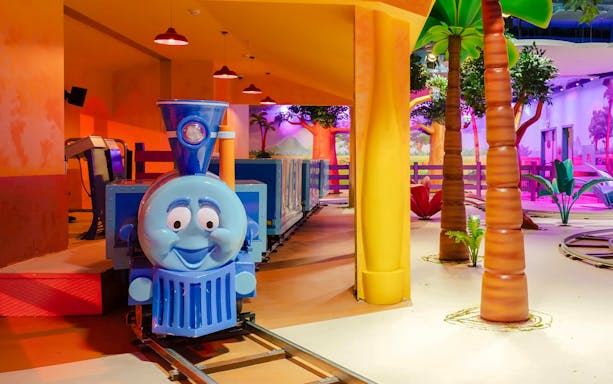 Train ride inside Nickelodeon Play City, Istanbul with colorful decor and palm trees.