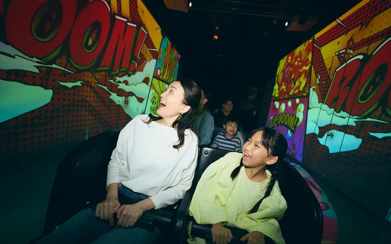 Friends enjoying a ride at Tokyo Dome City with comic-themed visuals.