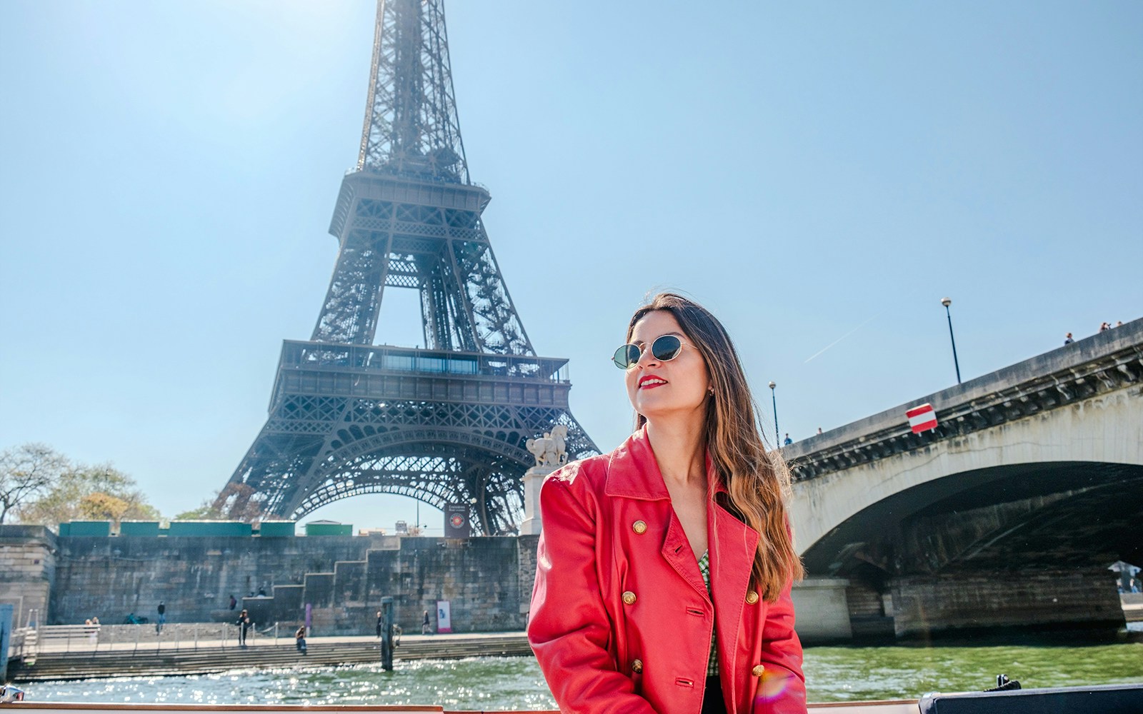 Lady enjoying the Official Emily in Paris Champagne Seine Cruise with Eiffel Tower in background.