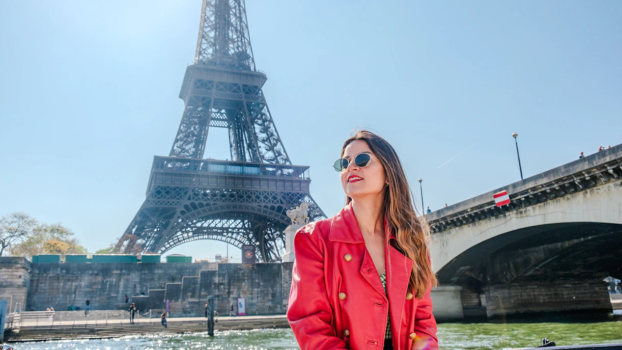 Lady enjoying the Official Emily in Paris Champagne Seine Cruise with Eiffel Tower in background.
