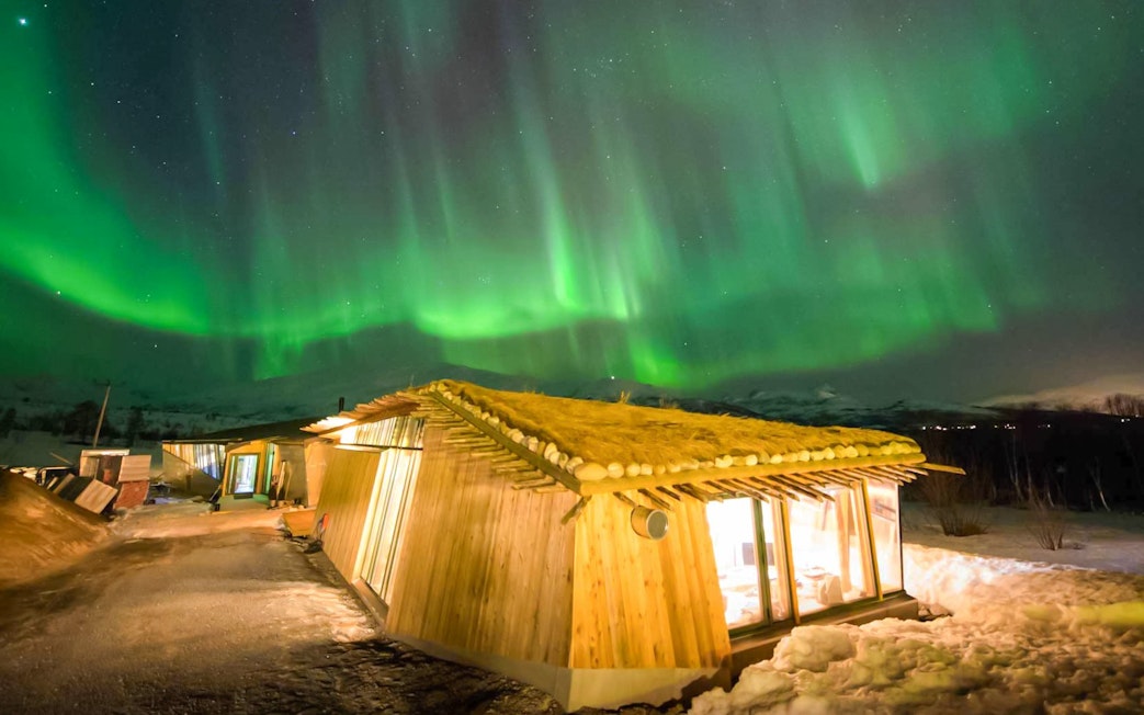 Traditional Gamme hut under Northern Lights in Tromso, Norway.