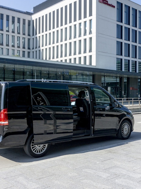 Black van parked at Krakow Airport terminal for private transfer service.