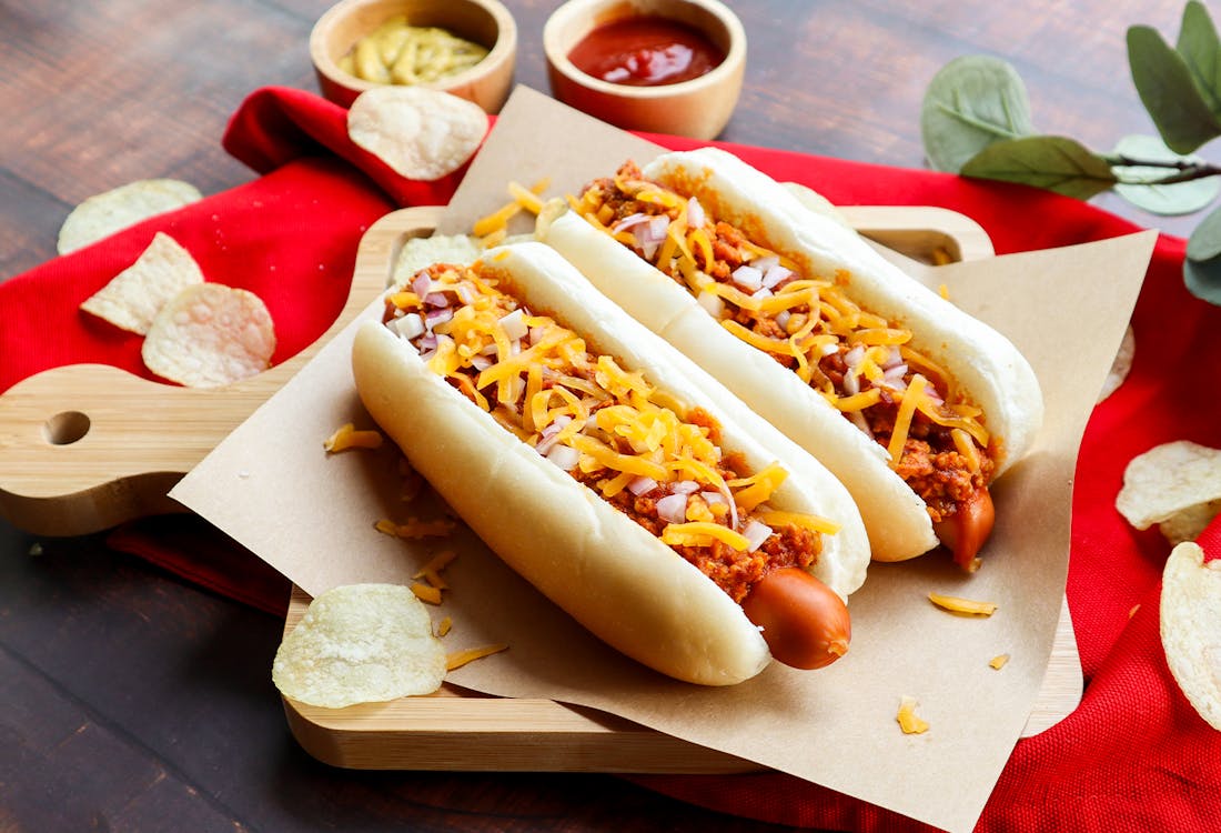 Chili hot dog with melted cheese and herbs.