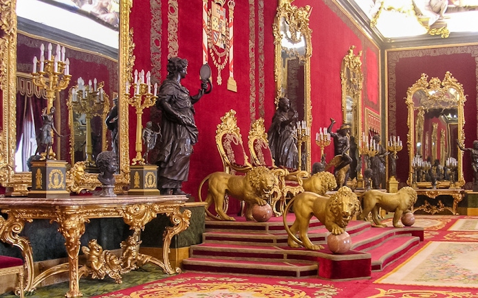 Throne room with ornate red and gold decor at Royal Palace of Madrid.