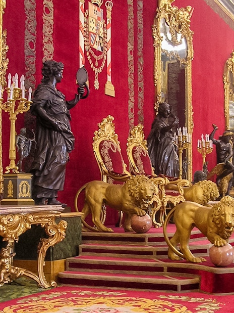 Throne room with ornate red and gold decor at Royal Palace of Madrid.