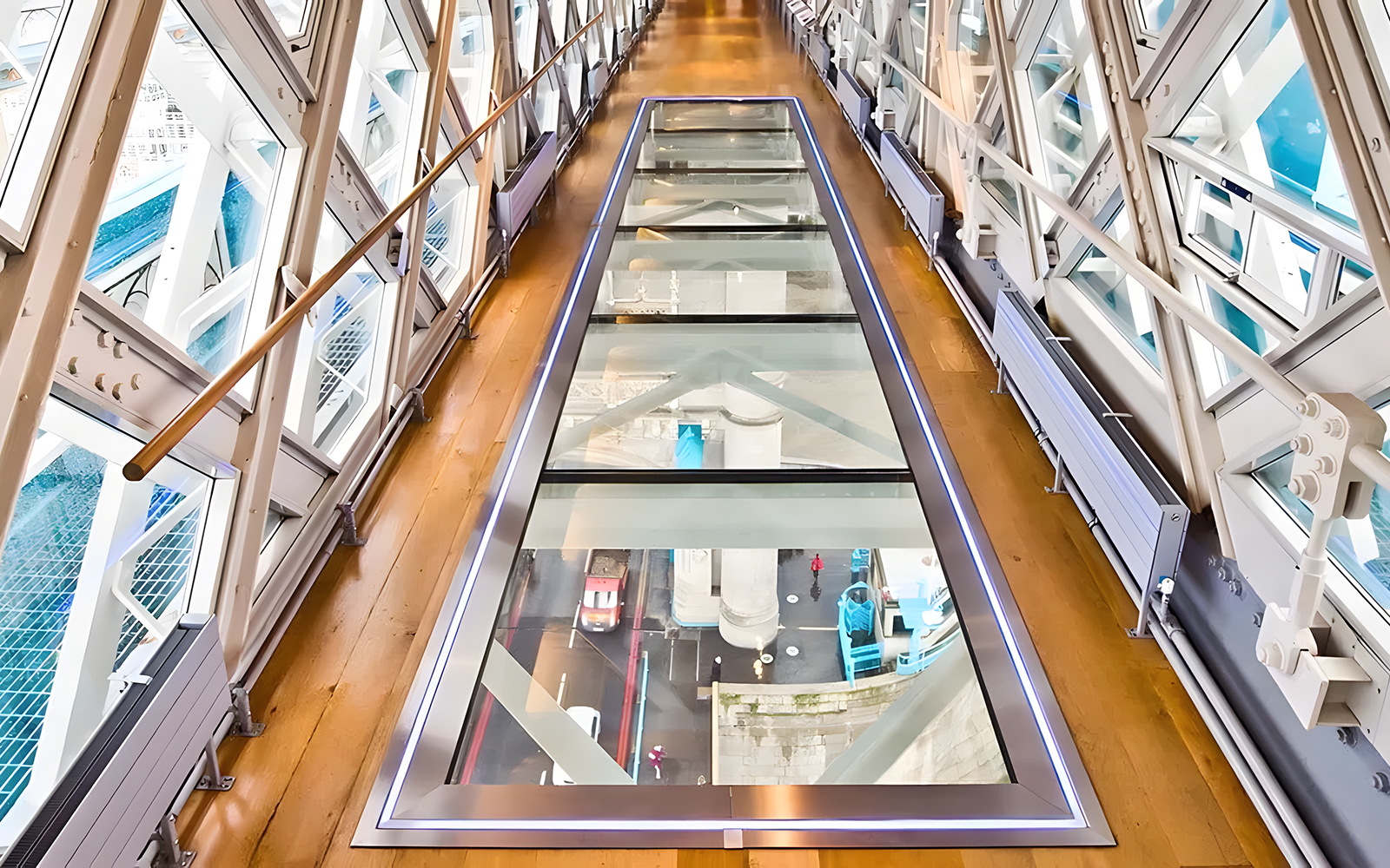 Glass walkway inside Tower Bridge, London, with view of the road and river below.