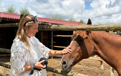 Woman petting a horse at a Tuscan farm during a food and wine tour with San Gimignano visit.