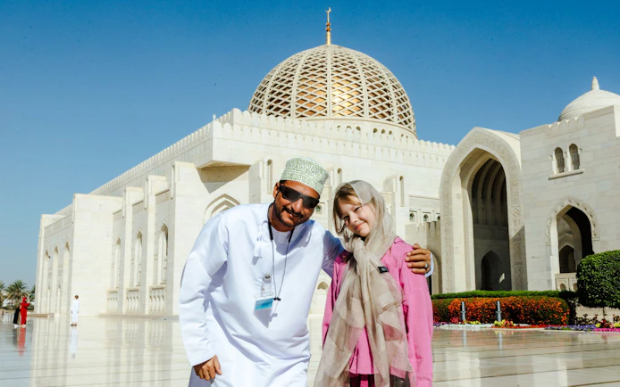 Guide with tourists at Sultan Qaboos Grand Mosque, Oman.