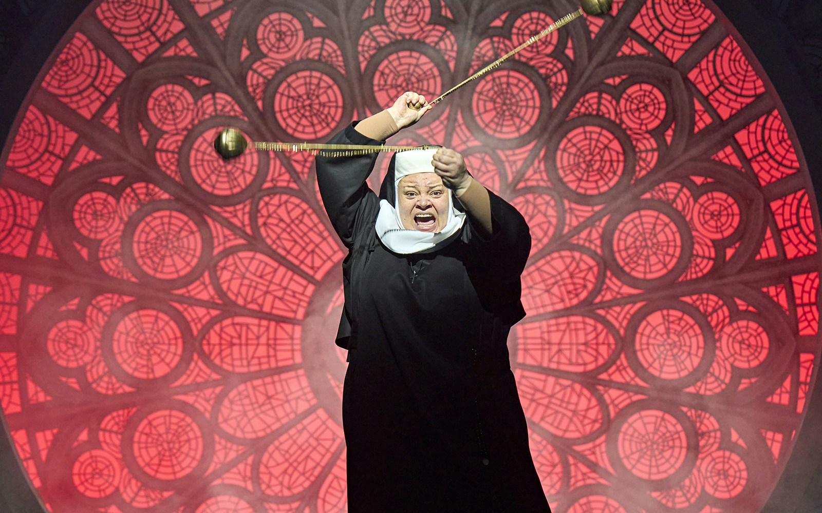 Nun performing on stage during Sister Act musical with stained glass backdrop.