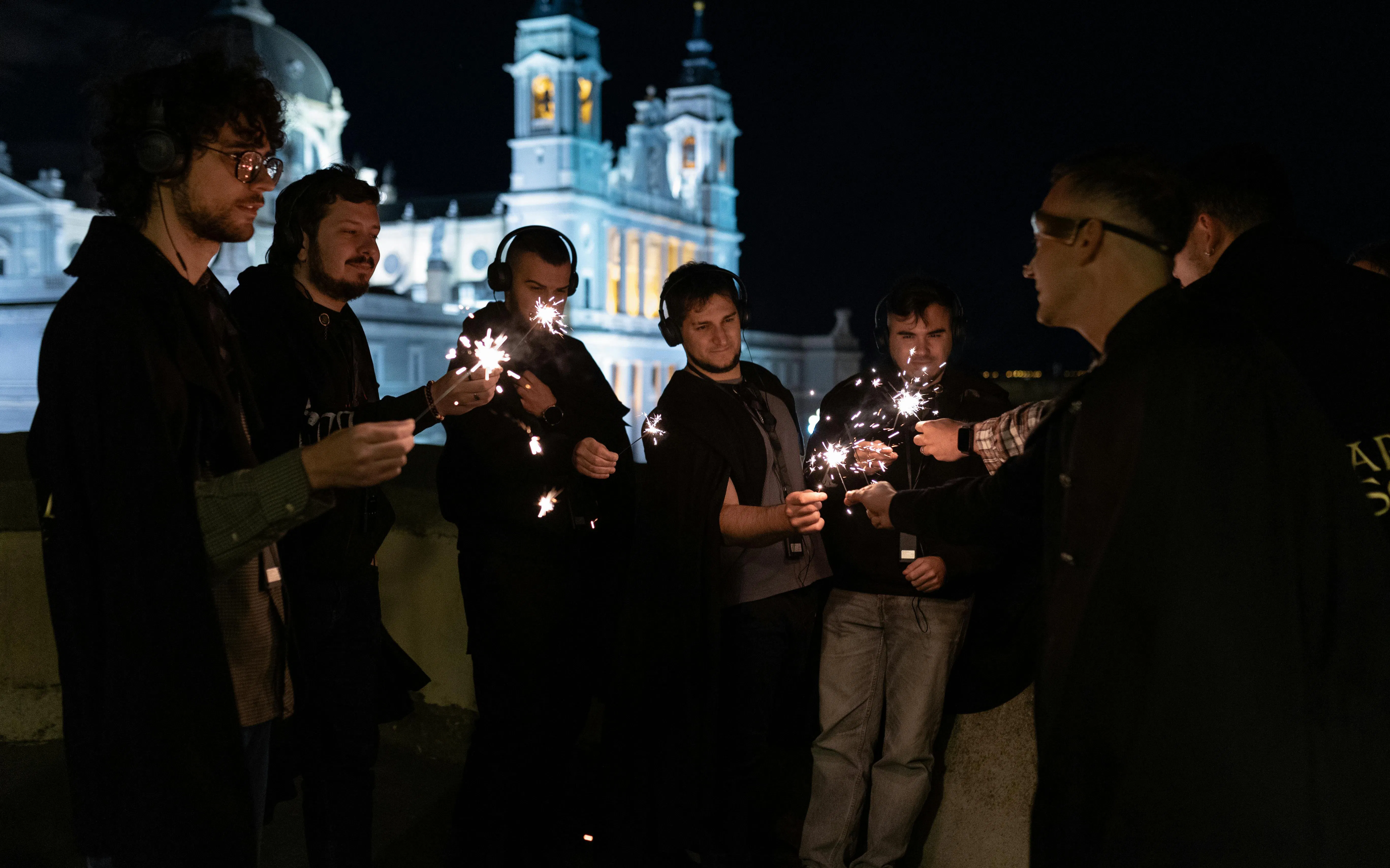 Tourists holding sparklers during a theatrical tour in Madrid at night.