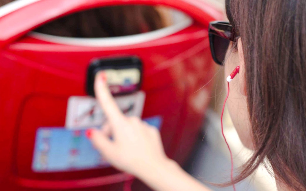 Woman using audio guide on a red hop-on hop-off bus tour.