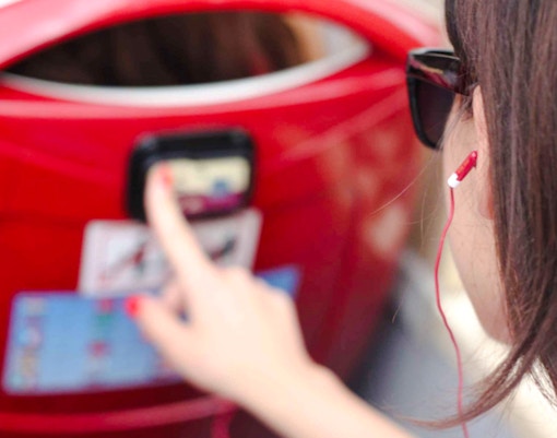 Woman using audio guide on a red hop-on hop-off bus tour.