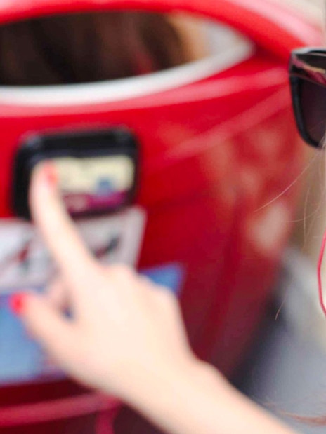 Woman using audio guide on a red hop-on hop-off bus tour.
