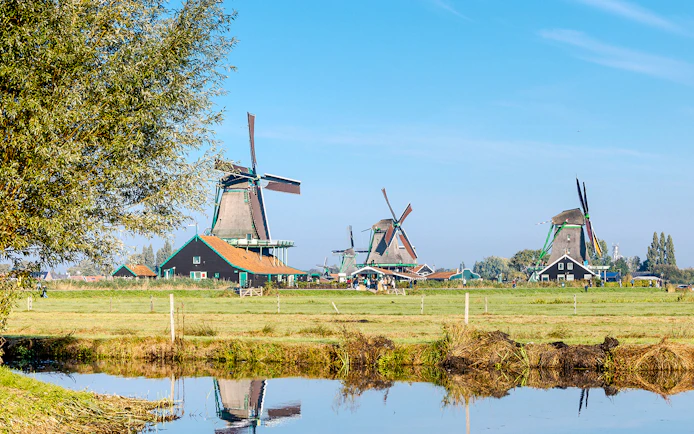 Windmills at Zaanse Schans with a reflection in the water, Netherlands.