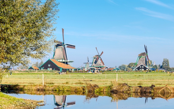 Windmills at Zaanse Schans with a reflection in the water, Netherlands.