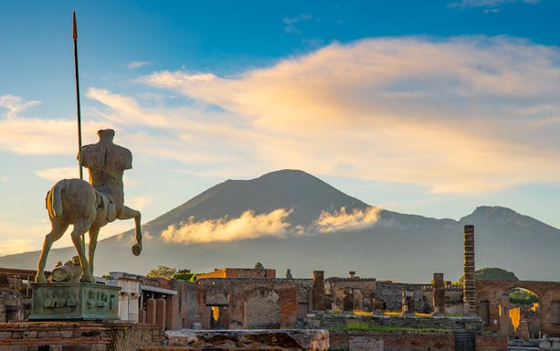 Statue of centaur in Pompeii ruins with Mount Vesuvius in background.