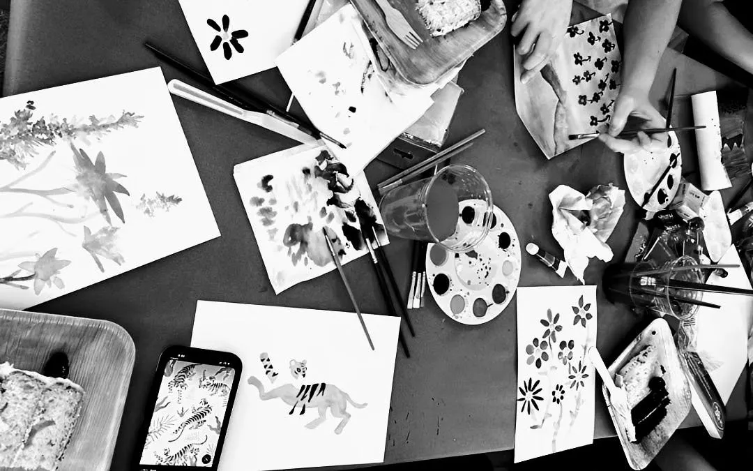Participants painting at a Barcelona sip and paint night with art supplies and drinks on the table.