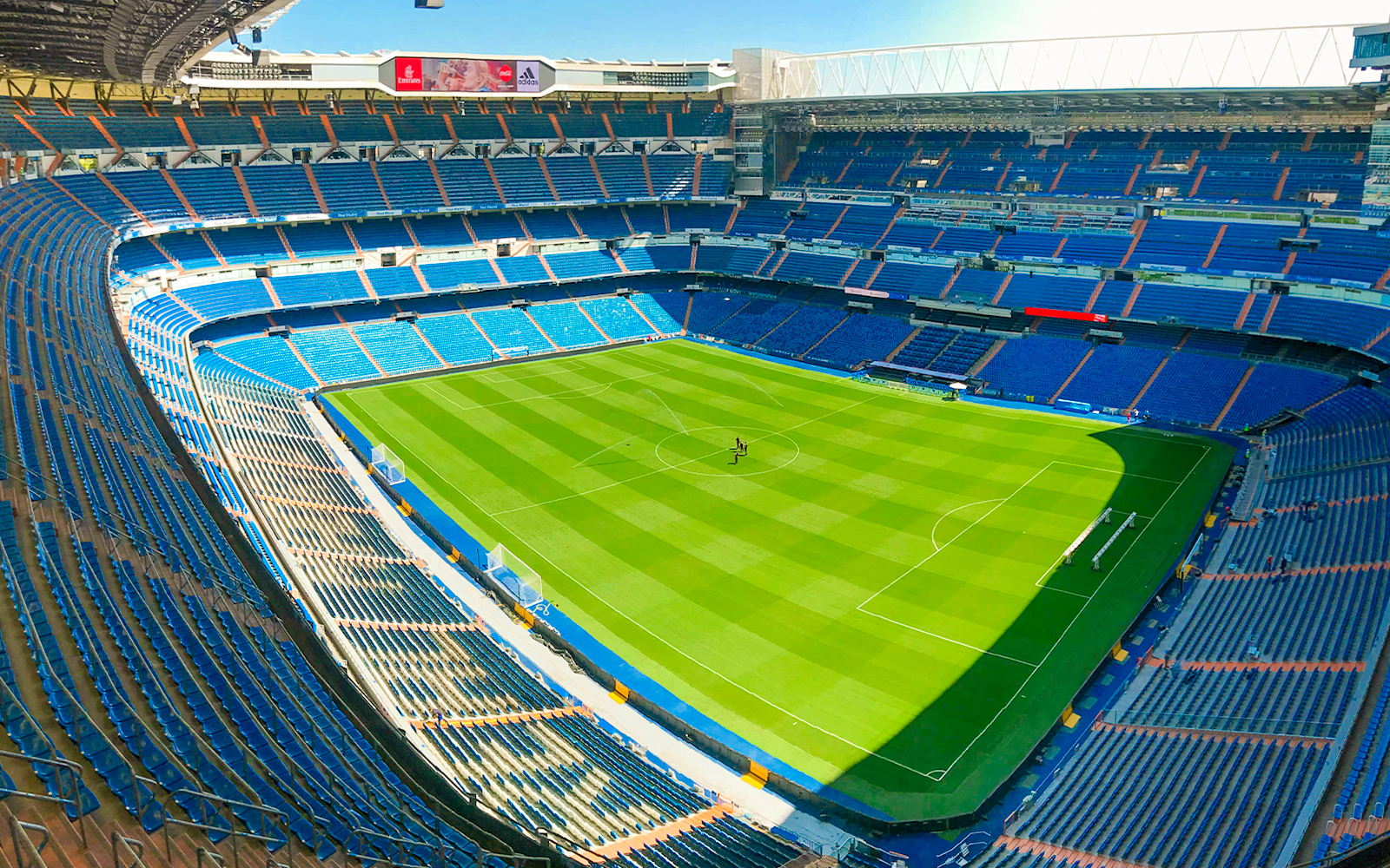 Santiago Bernabeu stadium view from stand, showcasing empty seats and green pitch.