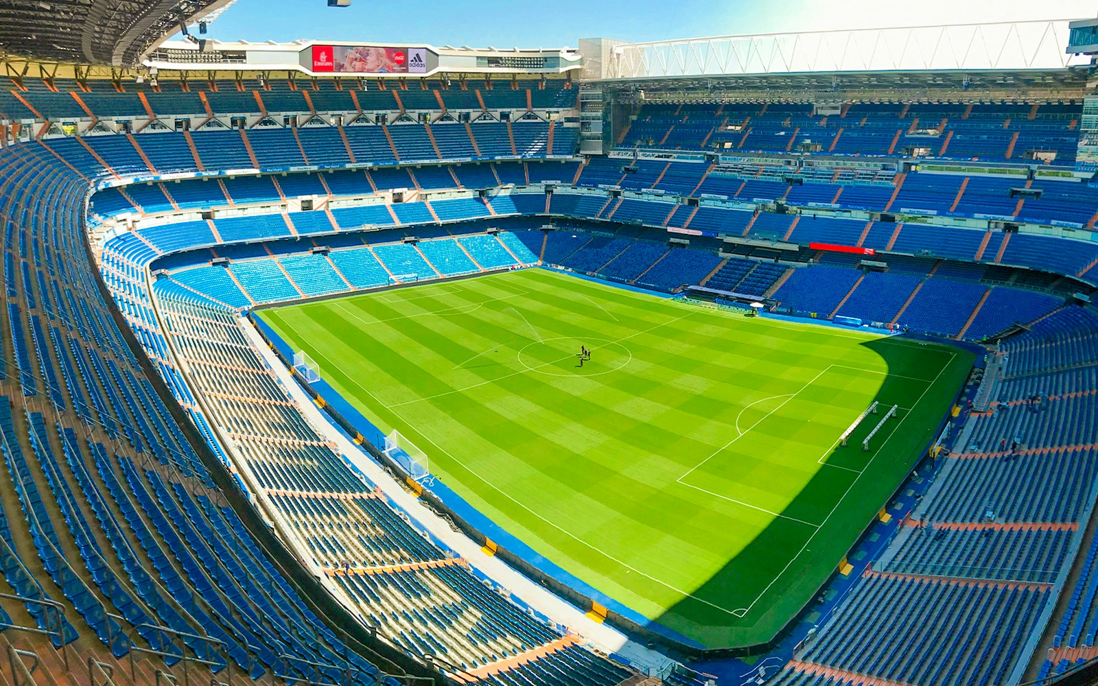 Santiago Bernabeu stadium view from stand, showcasing empty seats and green pitch.