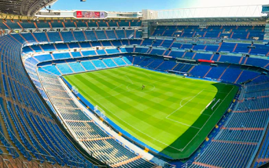 Santiago Bernabeu stadium view from stand, showcasing empty seats and green pitch.