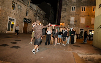 Group enjoying Split pub crawl with welcome shots and drink specials in a lively street.