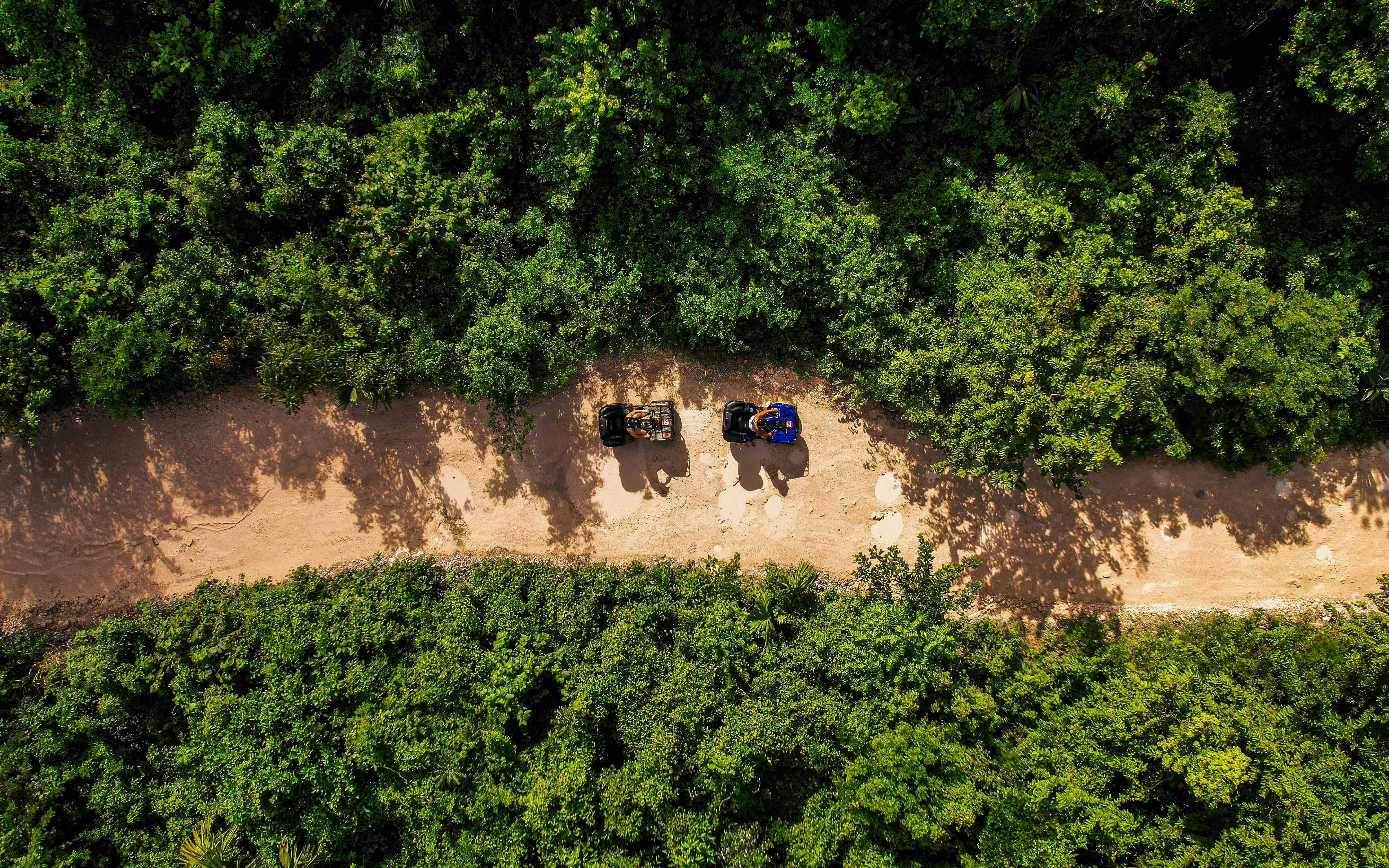 ATVs on a dirt path surrounded by dense greenery in Cancun Extreme Adventuring Park.