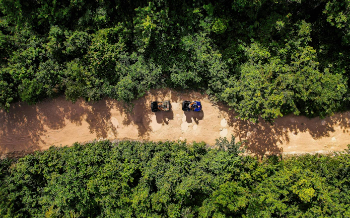 ATVs on a dirt path surrounded by dense greenery in Cancun Extreme Adventuring Park.