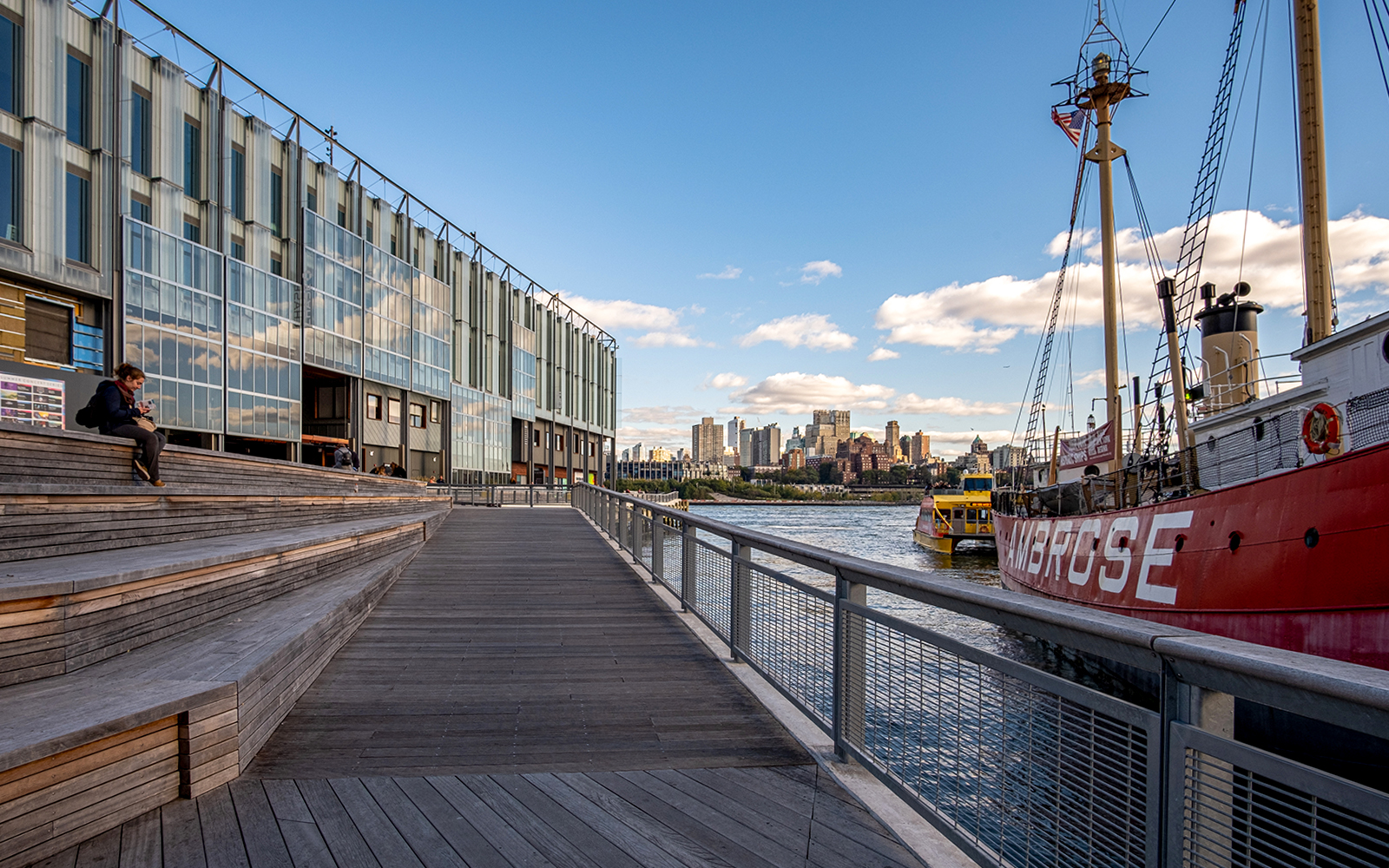 Waterfront view of South Street Seaport with historic ship Ambrose, New York City skyline in background.