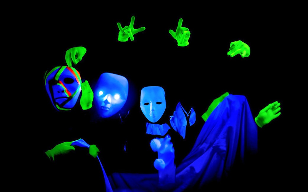 Performers with masks and gloves in Prague black light theatre.