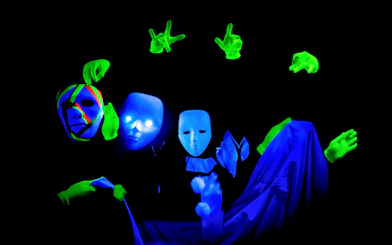 Performers with masks and gloves in Prague black light theatre.