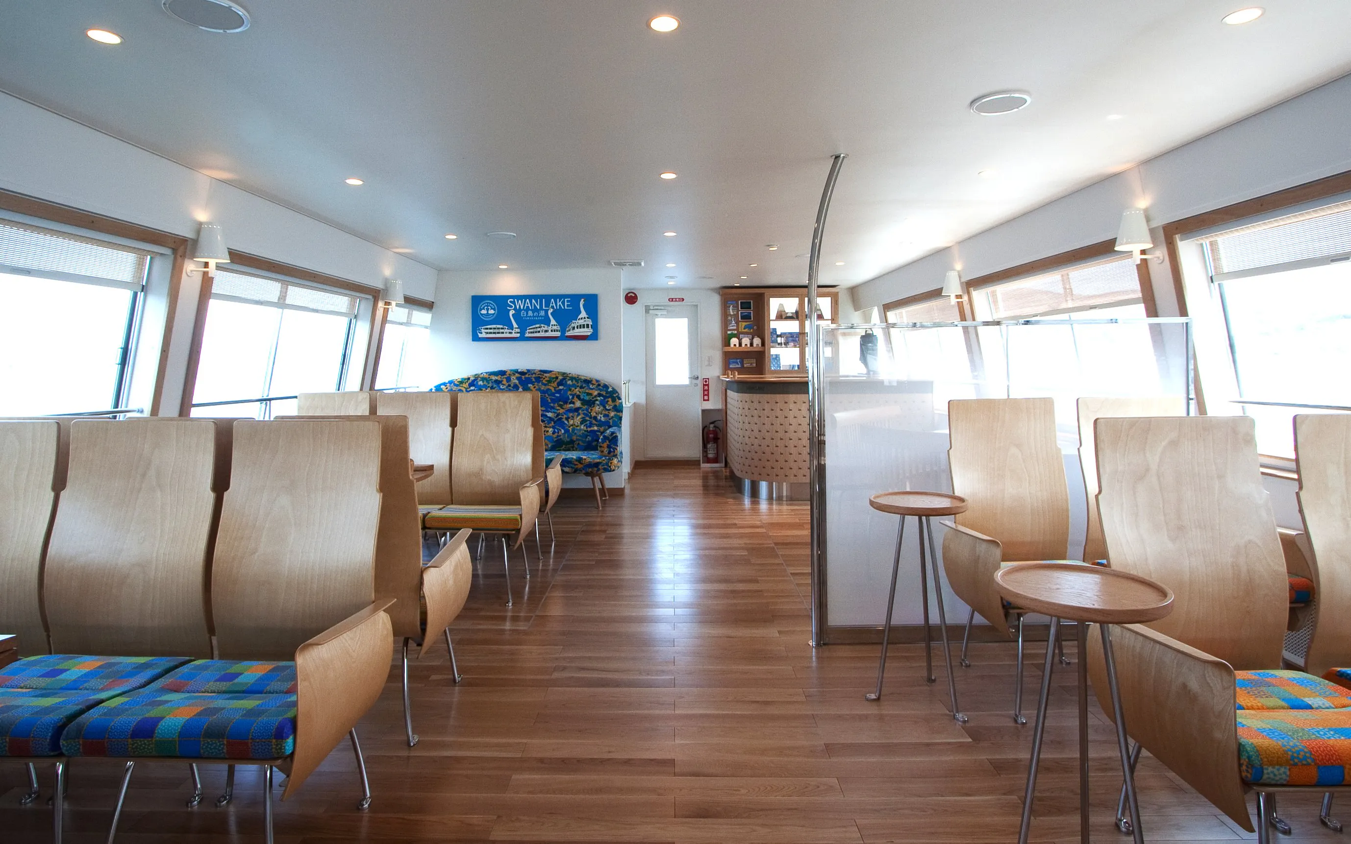 Interior seating area of Lake Yamanaka Swan Lake cruise ship with wooden chairs and tables.